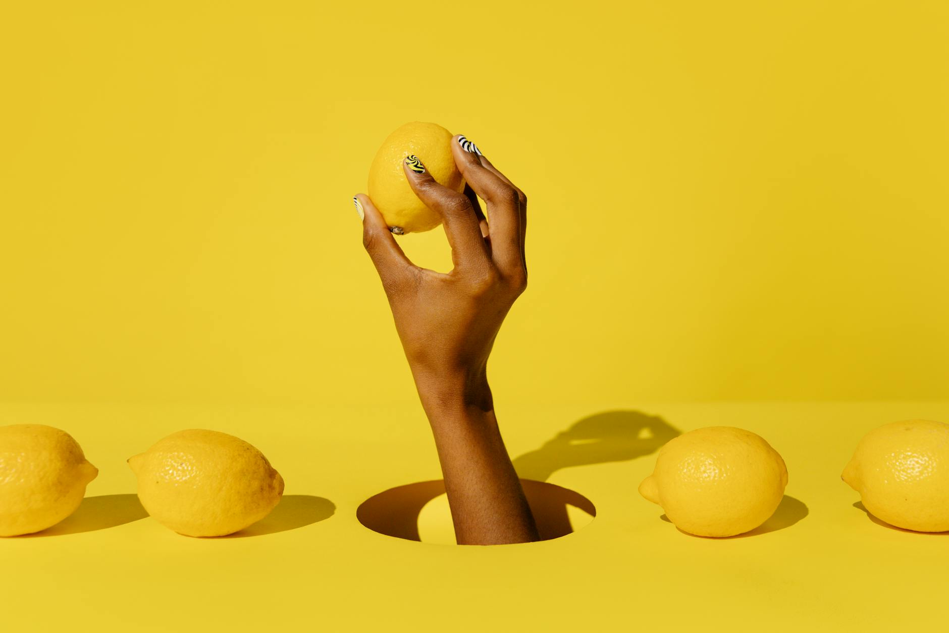 A hand holding a fresh lemon against a bright yellow background, symbolizing the refreshing sensation of restored pleasure.