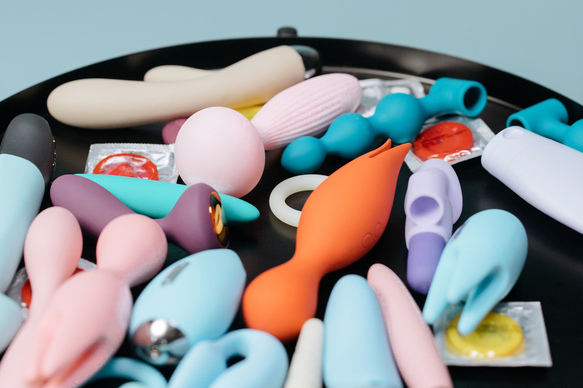 A vibrant collection of various sex toys including lemon clitoral vibrators on a black tray, featuring diverse shapes and colors.