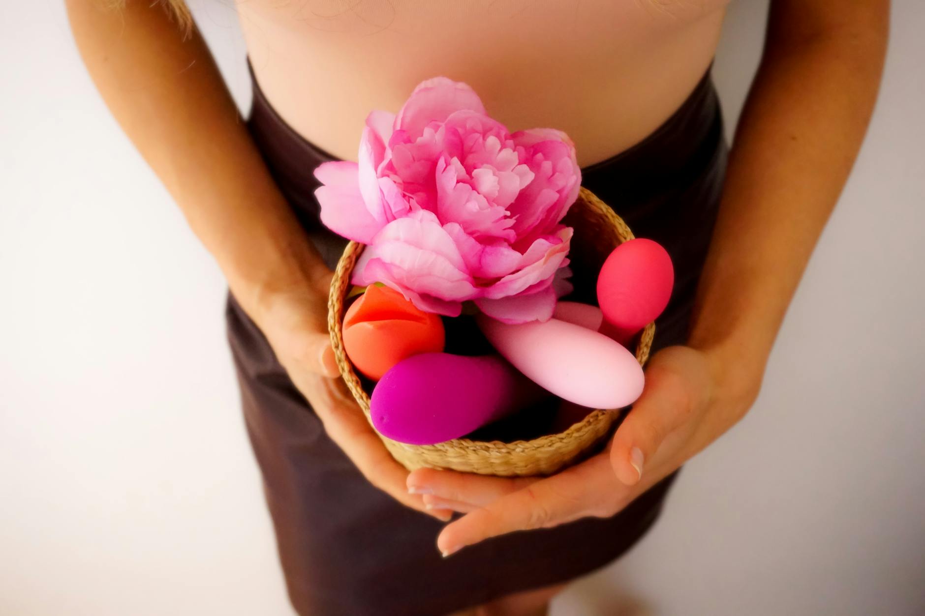 A hand holding a lemon against a soft pink background, representing the lemon vibrator's design philosophy